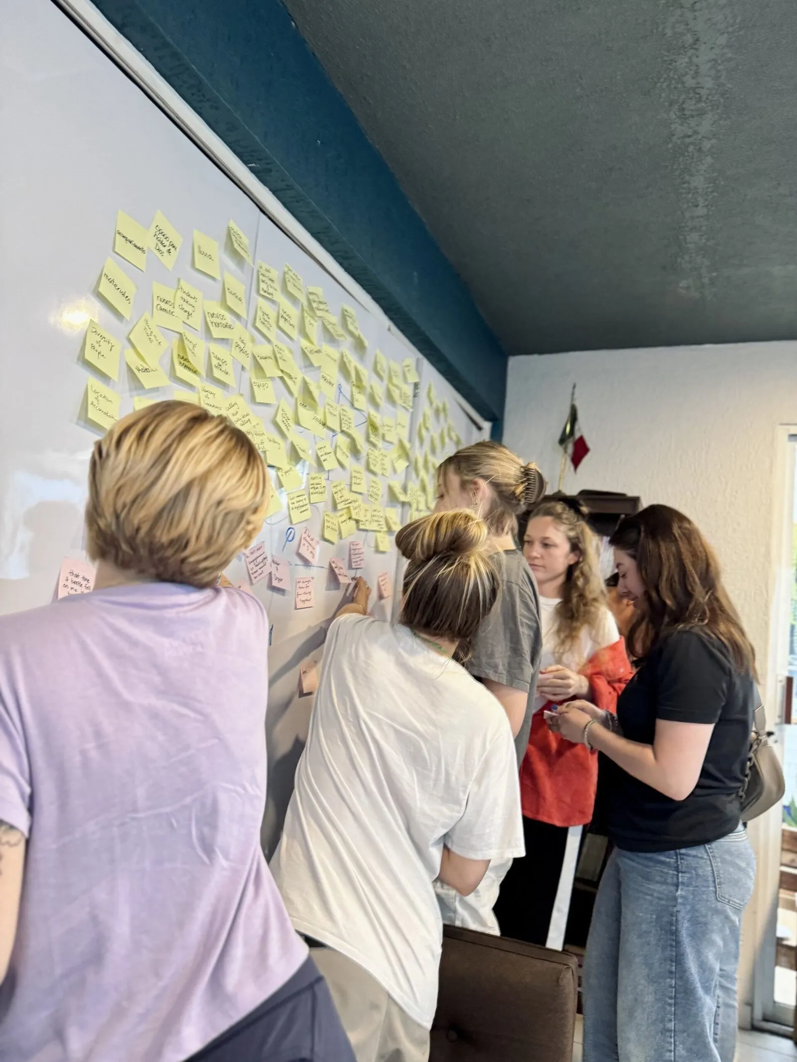 Justice School students working together at a whiteboard covered in sticky notes